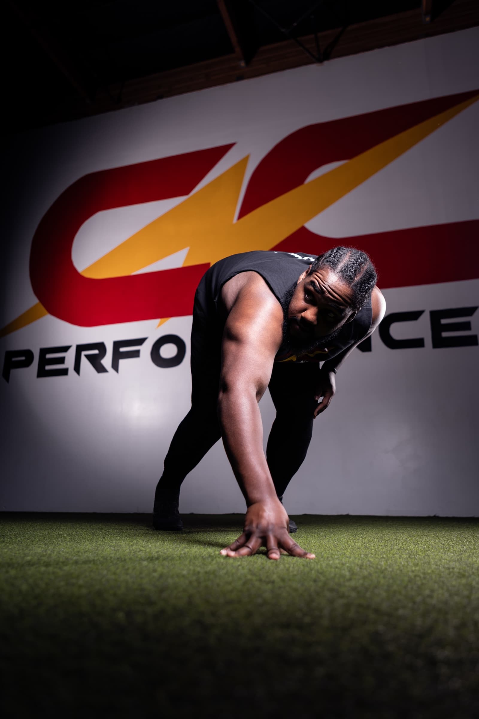 Coach Coop in a sprint stance in front of the CNC Performance wall